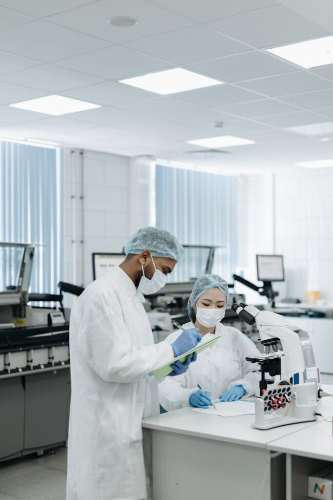 Researchers in protective gear working on a microscope in a laboratory, showcasing modern scientific research.